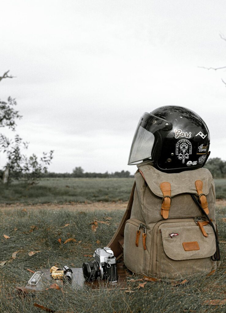 13 Best Tips For Hitchhiking (Beginners) Traveler rucksack with motorcycle helmet on grassy field