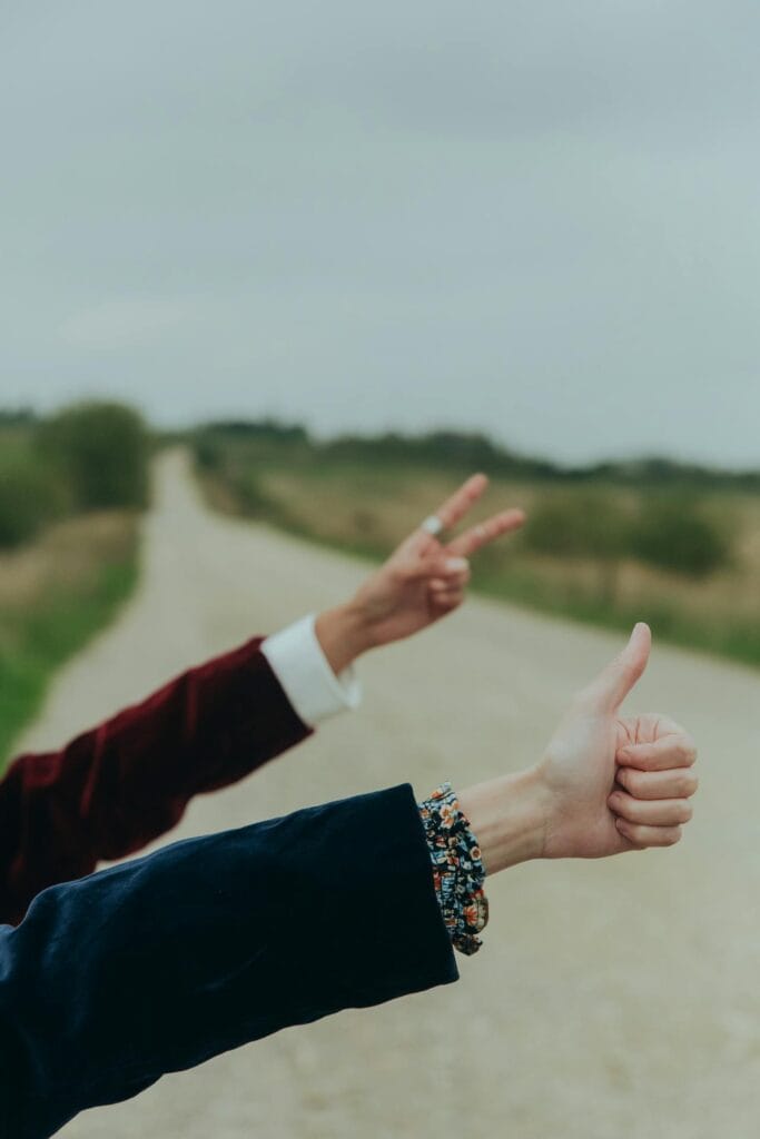 13 Best Tips For Hitchhiking (Beginners) girls showing hitchiking hand gesture