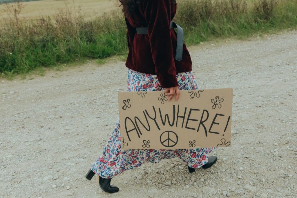 13 Best Tips For Hitchhiking (Beginners) girl traveler having a board in their hand that says "anywhere"